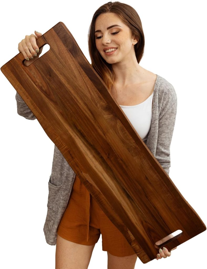 A woman holds a large rectangular wooden serving tray with handles on both ends, perfect for carrying essentials to an outdoor cooking station.