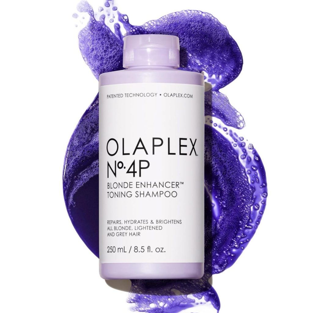 A bottle of Olaplex No. 4P Blonde Enhancer Toning Shampoo is placed on a swirl of vibrant purple liquid, adding a festive touch perfect for your Easter Brunch beauty routine.
