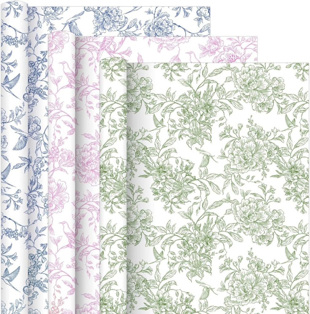 Three sheets of vintage wrapping paper with floral patterns in blue, pink, and green are layered, each featuring intricate botanical designs on a white background.