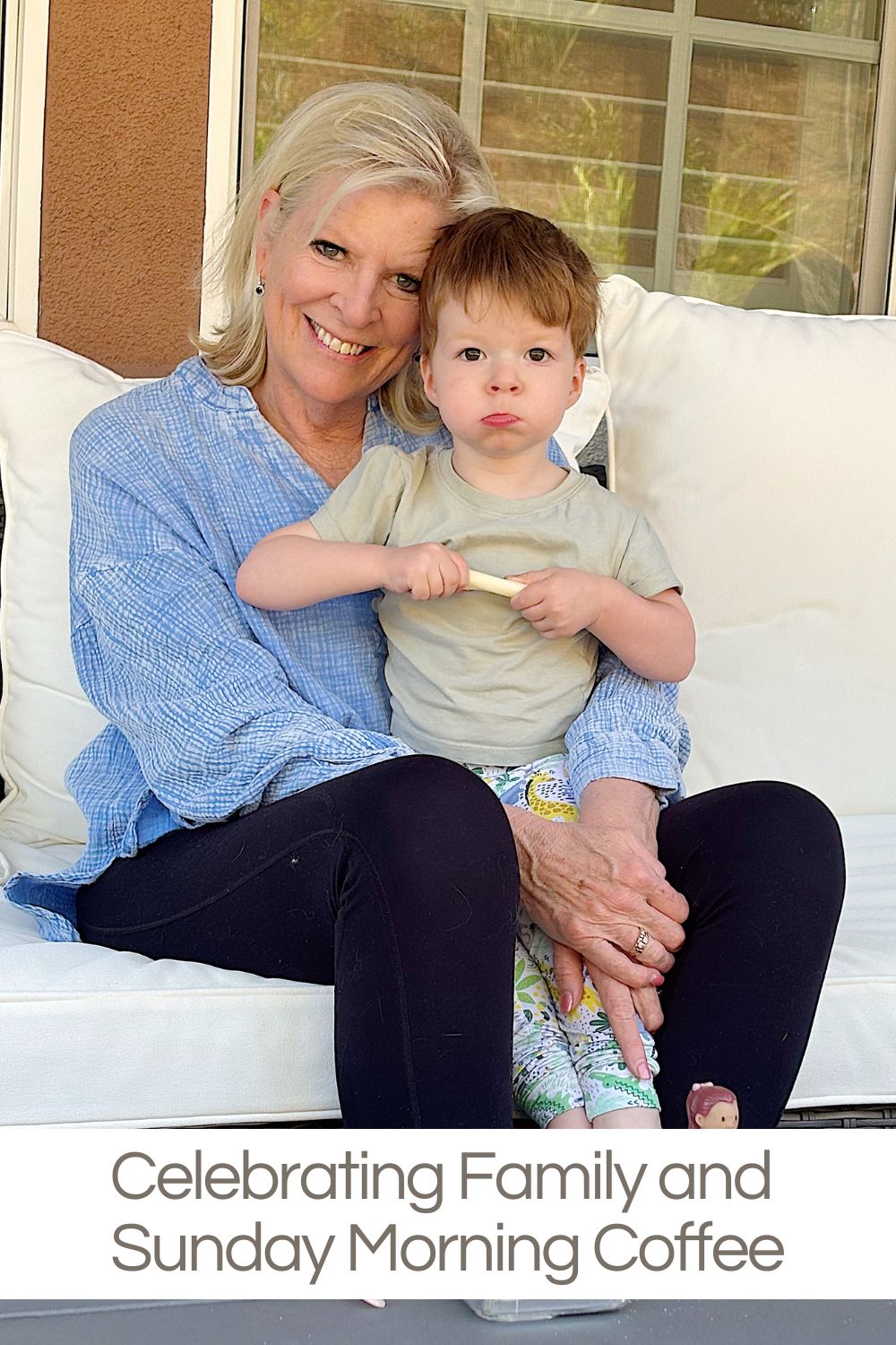Elderly woman smiling and holding a toddler on her lap, sitting on a white outdoor bench. Text reads: "Celebrating Family and Sunday Morning Coffee.