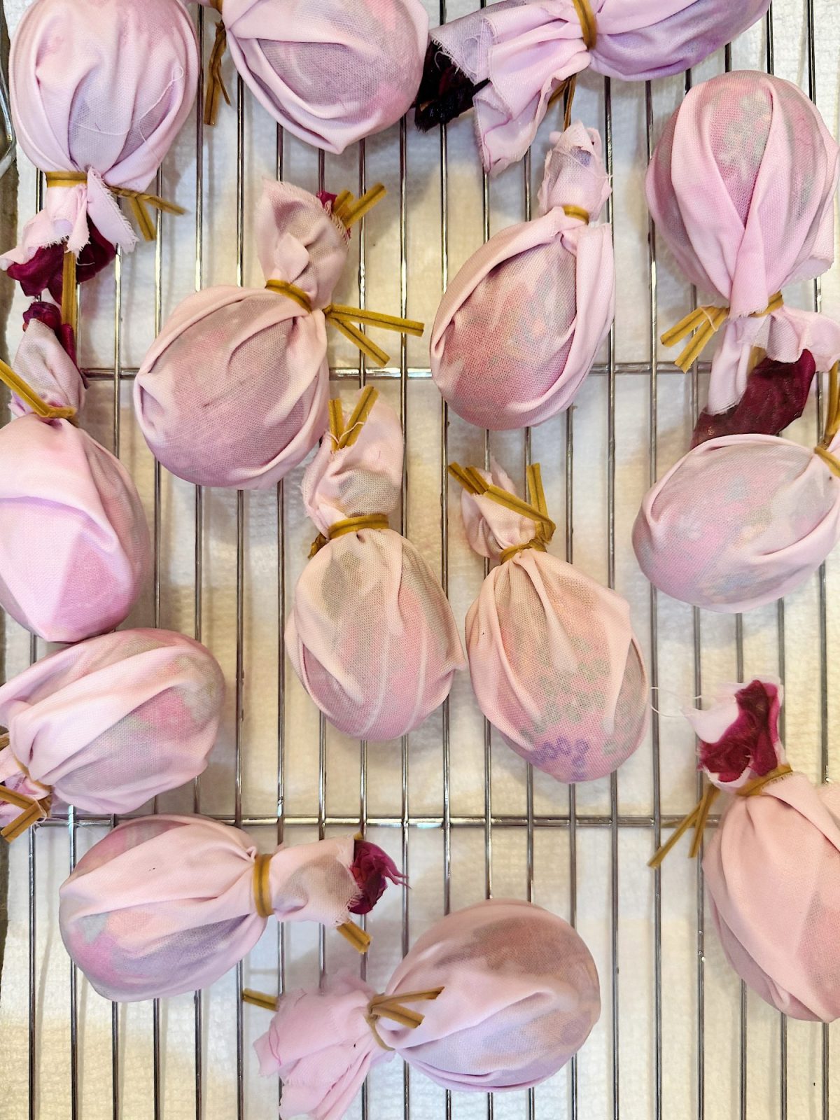 Several fabric-wrapped bundles tied with string are placed on a metal cooling rack.
