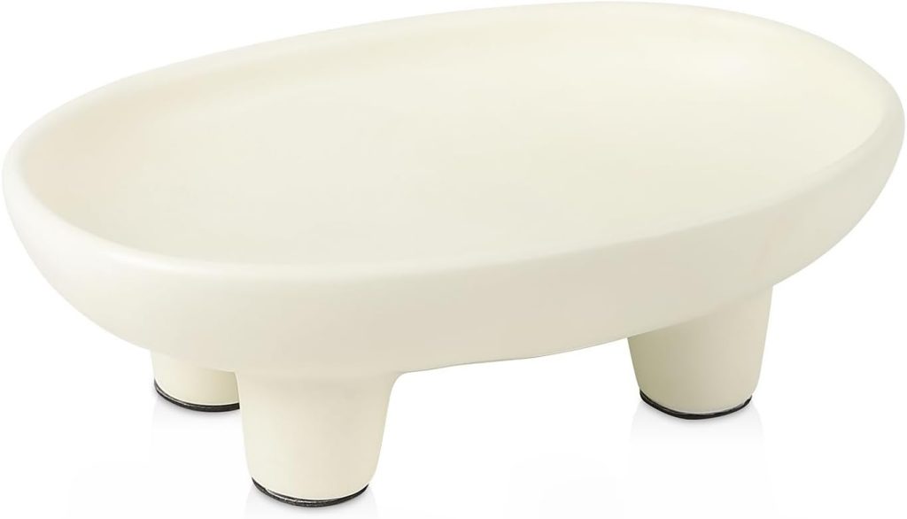 Oval-shaped white ceramic soap dish with three short legs and a smooth surface, perfect for holding soap or used as a stylish tray for tea bags.