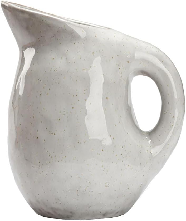 A small, round ceramic pitcher with a handle and spout, featuring a glossy, speckled white glaze—perfect for adding charm to your open concept kitchen.