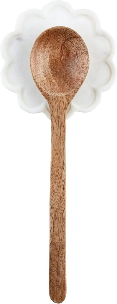 A wooden spoon rests on a white, flower-shaped spoon rest—an effortless touch for your summer decorating ideas.