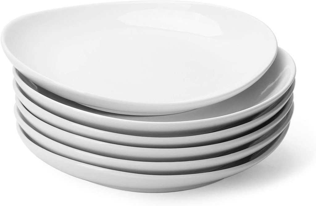 A stack of six white, oval-shaped ceramic plates arranged neatly on top of each other—perfect for serving guests at your next salad bar ideas gathering.