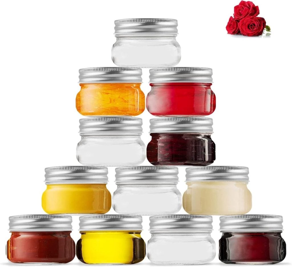 A pyramid of twelve small glass jars with silver lids, some filled with various colored substances—perfect for creative salad bar ideas—sits beneath a cluster of red roses in the top right corner.
