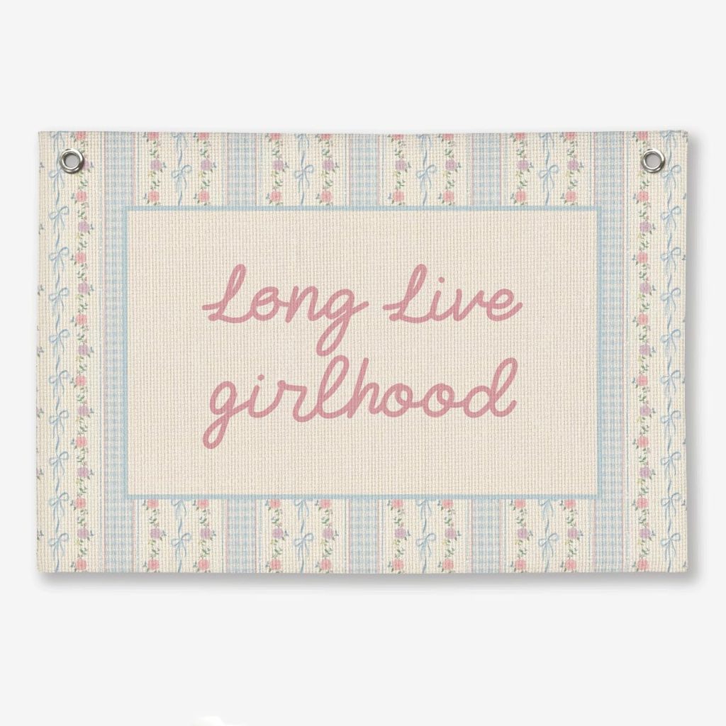 A rectangular fabric banner with a floral and striped pattern features the pink cursive text "long live girlhood" in the center—perfect for adding fun Summer Decorating Ideas to any space.