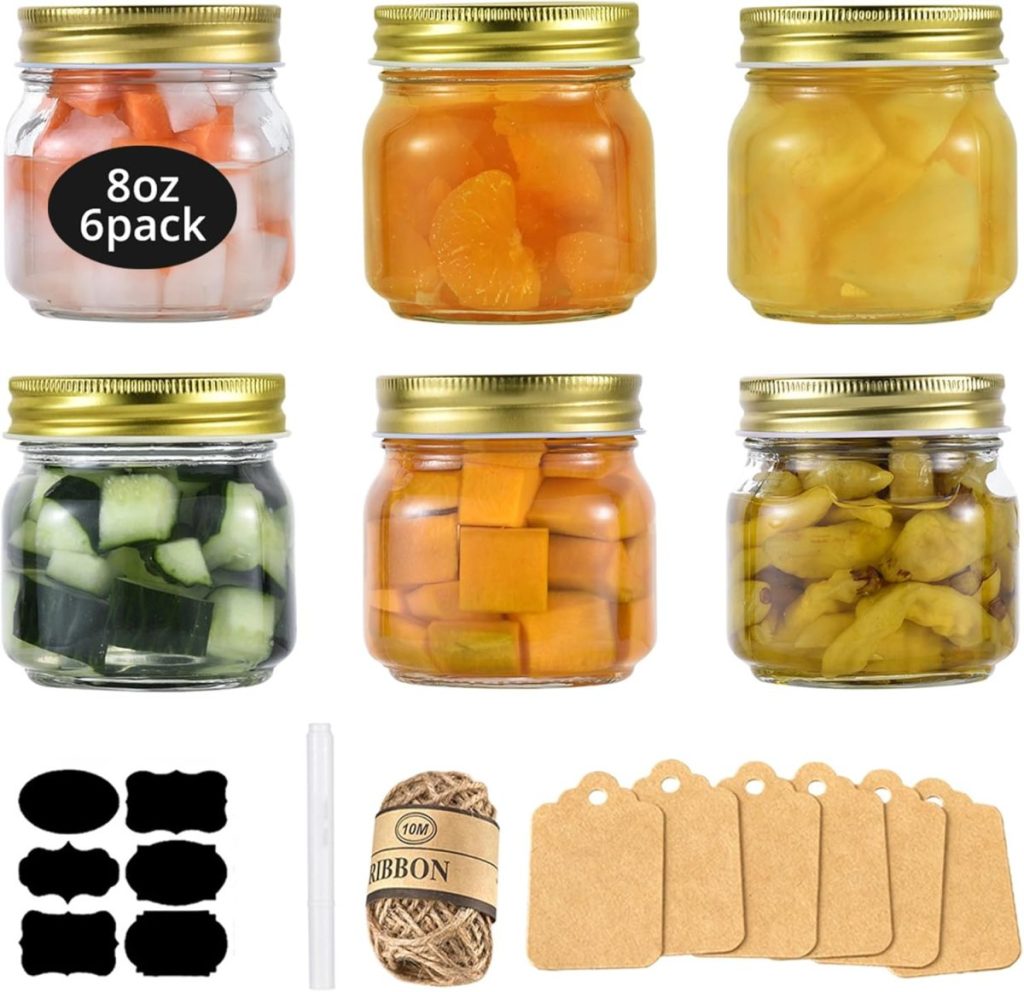 Six glass jars filled with various foods, each with a gold lid, are arranged in two rows. Below them are labels, a marker, twine, and five kraft paper tags—perfect for your next salad bar ideas or meal prep inspiration.