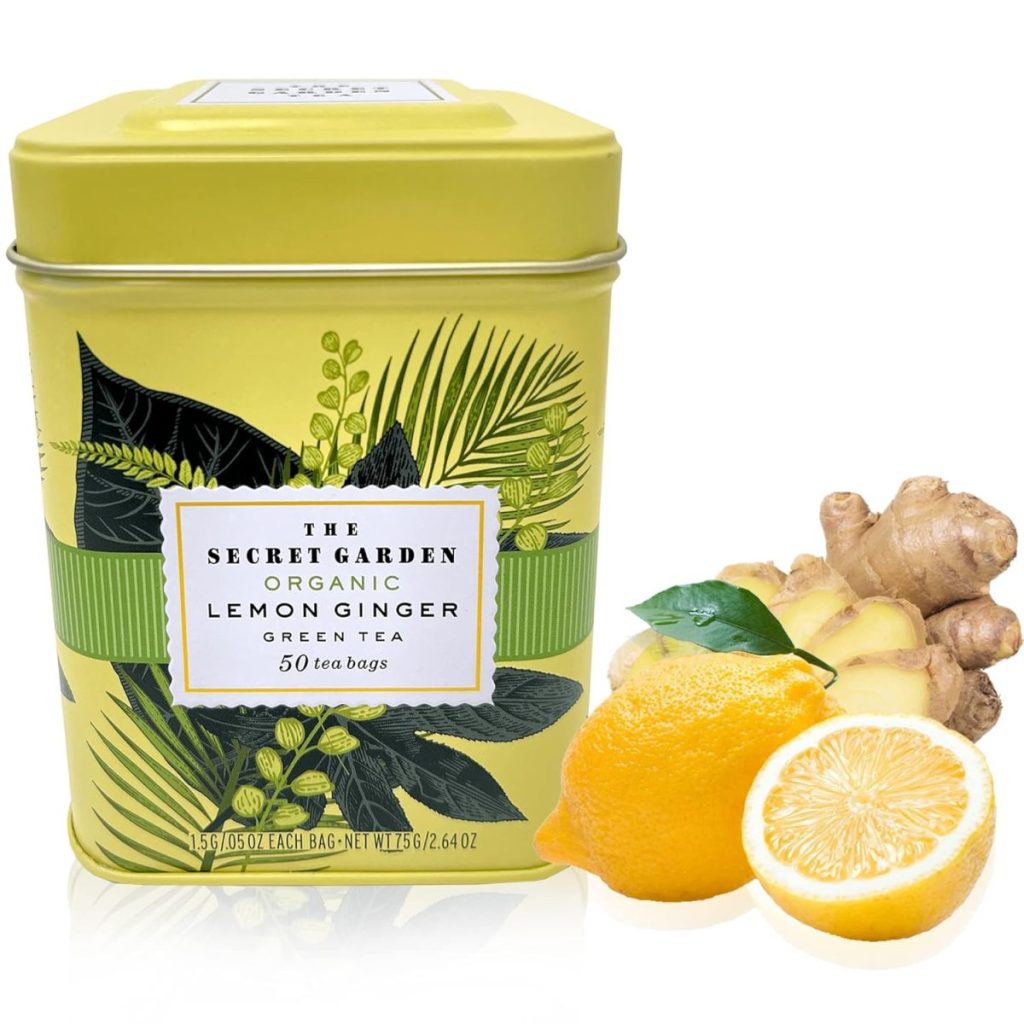 A yellow tin of The Secret Garden Organic Lemon Ginger Green Tea is shown next to fresh ginger root, a halved lemon, and its convenient tea bags.