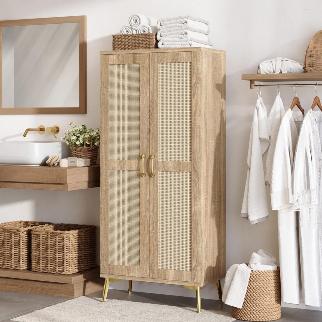 A wooden cabinet with rattan doors stands in a bathroom next to a rack of white robes, towels, baskets, and a sink with a mirror above it—perfect for fresh summer decorating ideas.