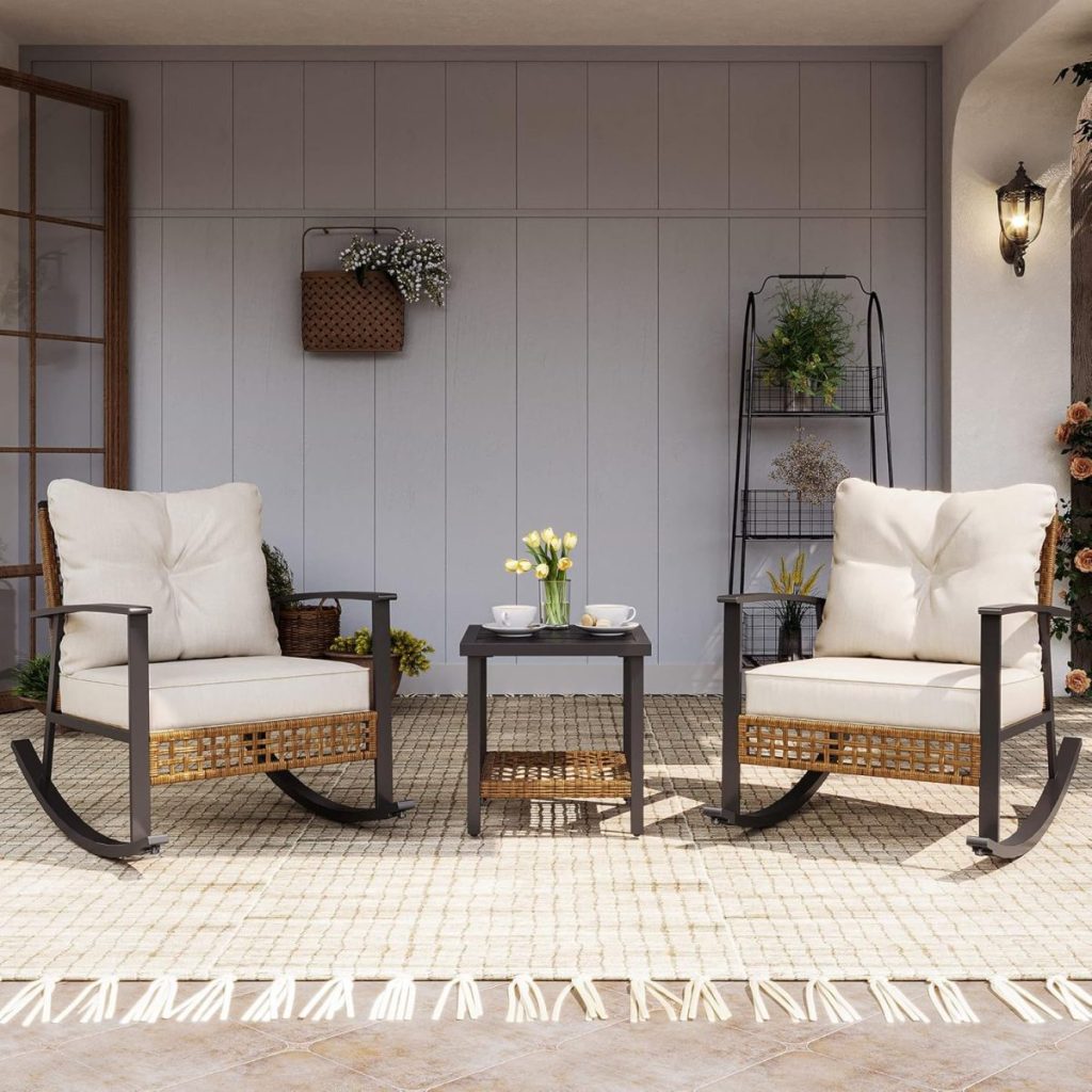 Two cushioned rocking chairs and a small table with flowers and cups are arranged on a patio with light walls and decorative plants, creating the perfect spot to relax after a lively pool party.