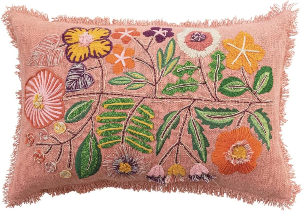 Rectangular pink pillow with fringed edges, decorated with colorful embroidered flowers and leaves in green, yellow, orange, purple, and pink—perfect for adding a cheerful touch to your summer decorating ideas.