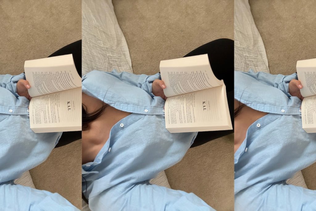 Person wearing a light blue shirt and black pants is lying on a beige carpet and reading an open book. The image is shown three times in a row.