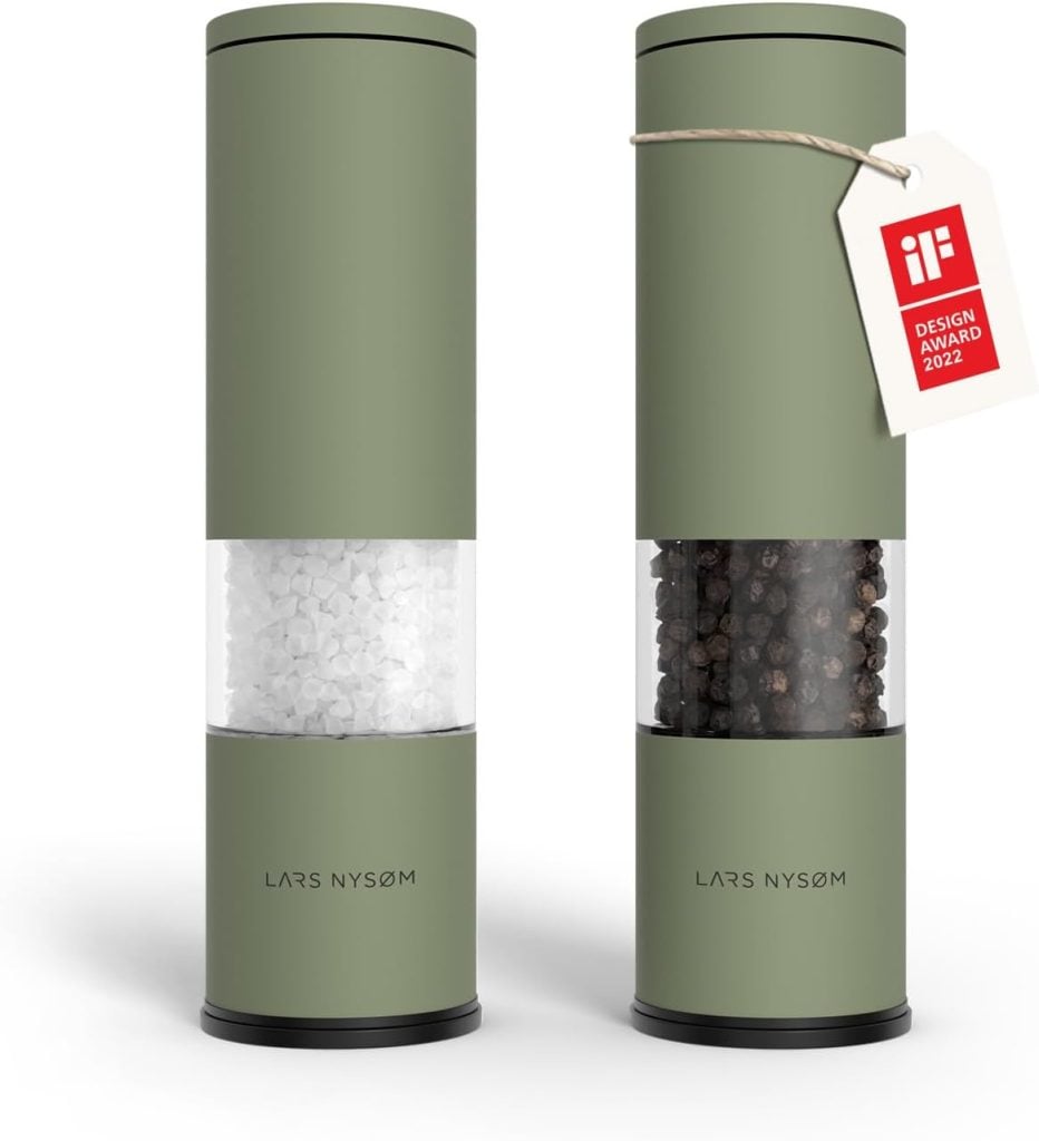 Two green cylindrical Lars Nys&oslash;m grinders, perfect for healthy summer recipes, stand side by side&mdash;one filled with salt, the other with pepper. The pepper grinder features a 2022 design award tag.