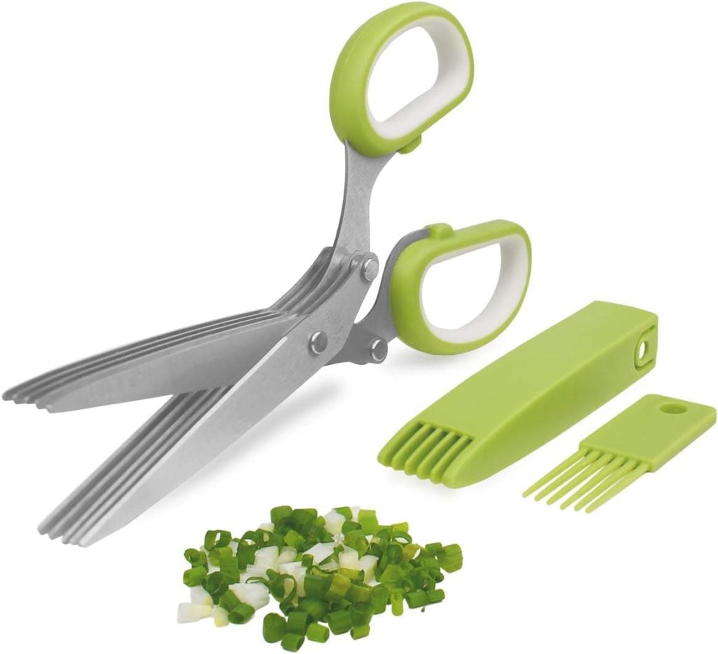 Multi-blade herb scissors with green and white handles, a cleaning comb, and chopped green onions on a white surface&mdash;perfect for prepping healthy summer recipes.