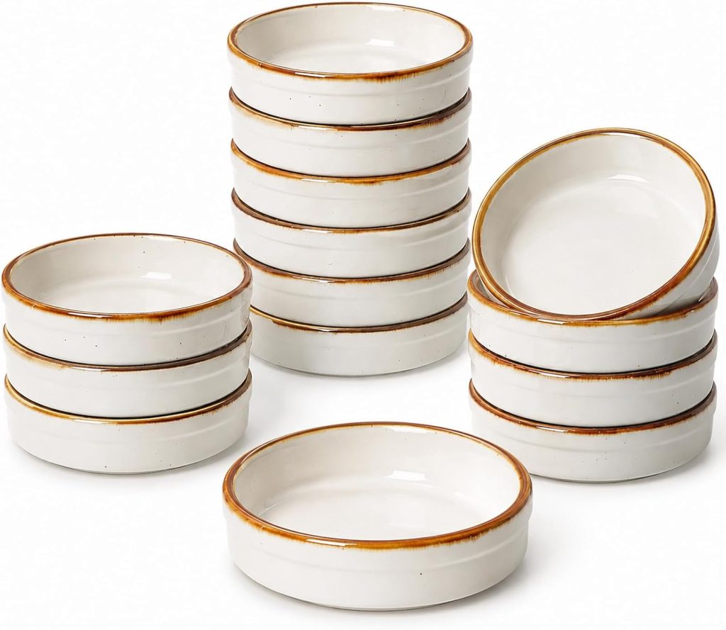 A group of fourteen stacked and unstacked white ceramic ramekins with brown rims, arranged on a plain background—perfect vessels for your favorite mini tart recipe.