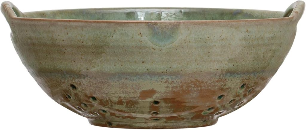 Green and brown ceramic colander bowl with handles and drainage holes along the bottom.