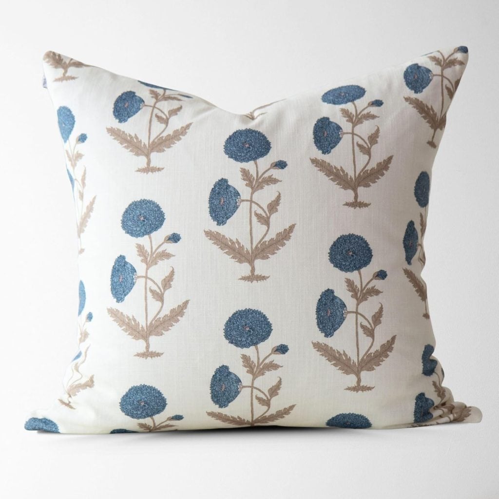 Square white pillow featuring a pattern of blue flowers with beige stems and leaves, perfect for interior designers seeking elegant accents against a plain white background.