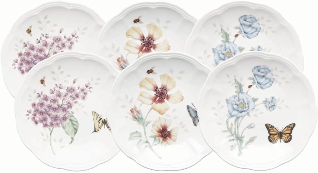 Six white ceramic plates featuring floral patterns and illustrations of butterflies and bees, arranged overlapping on a white background&mdash;perfect for serving homemade apple pie.