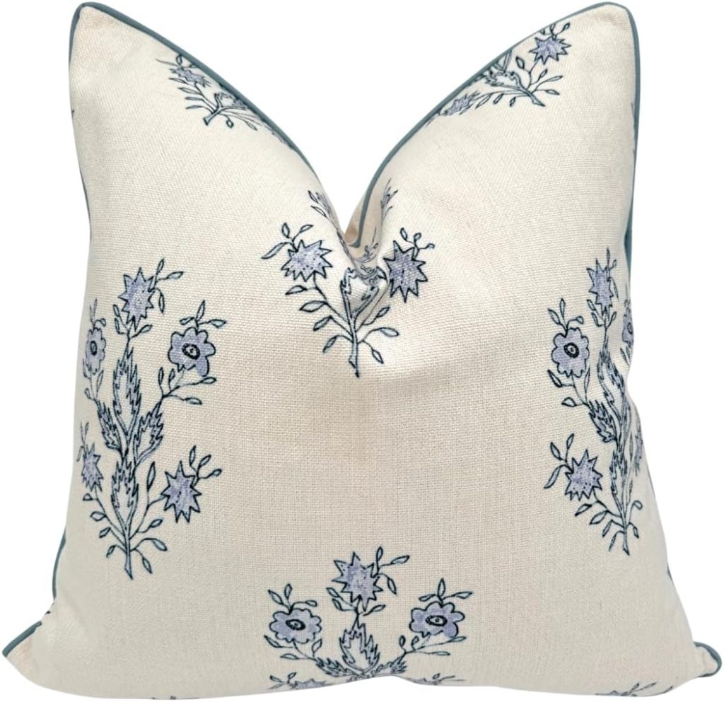 Square decorative pillow with a white background and blue floral pattern, shown upright with visible creases at the top corners—evoking the timeless, inviting style of a Nancy Meyers interior.