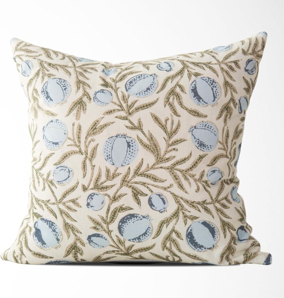 Square pillow with a cream background, decorated with a leafy and floral pattern in green and blue—a stylish accent piece favored by interior designers for elevating any living space.