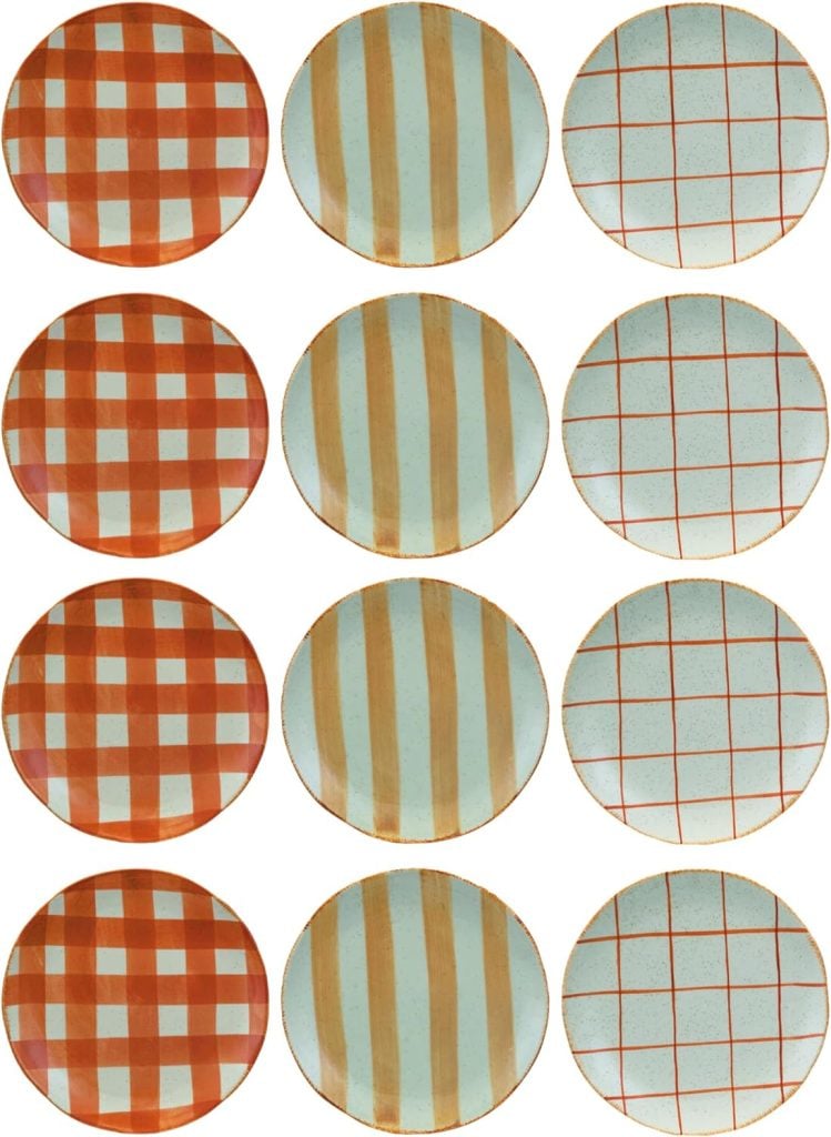 Twelve round plates are arranged in a 4x3 grid. Each plate displays a unique red and white checkered, striped, or grid pattern, with some designs reminiscent of playful creamsicle hues.