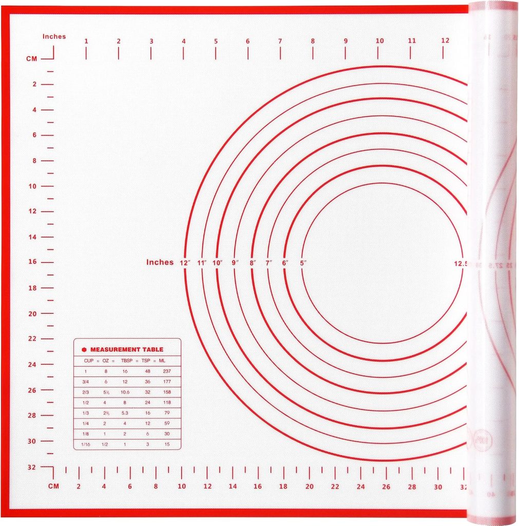 Red and white silicone baking mat with concentric measurement circles, rulers along edges in inches and centimeters, and a measurement conversion table—perfect for baking or working with air dry clay.