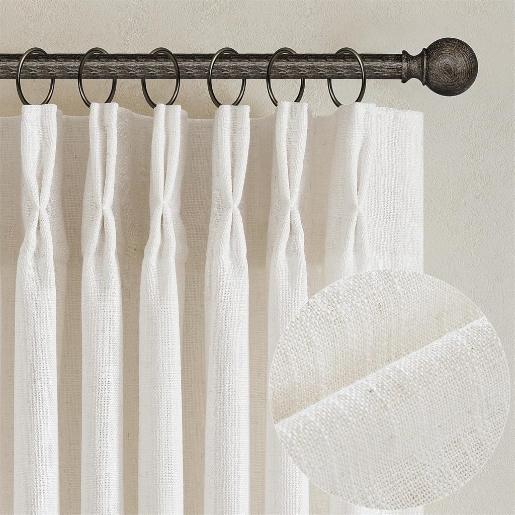 White linen curtains with pinch pleats hang from a dark metal rod with rings—an elegant choice often favored by interior designers; inset shows a close-up of the fabric texture.
