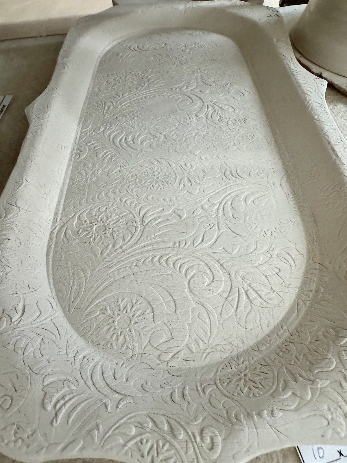 Rectangular ceramic tray with raised edges, featuring an intricate floral and leaf pattern embossed on its surface.
