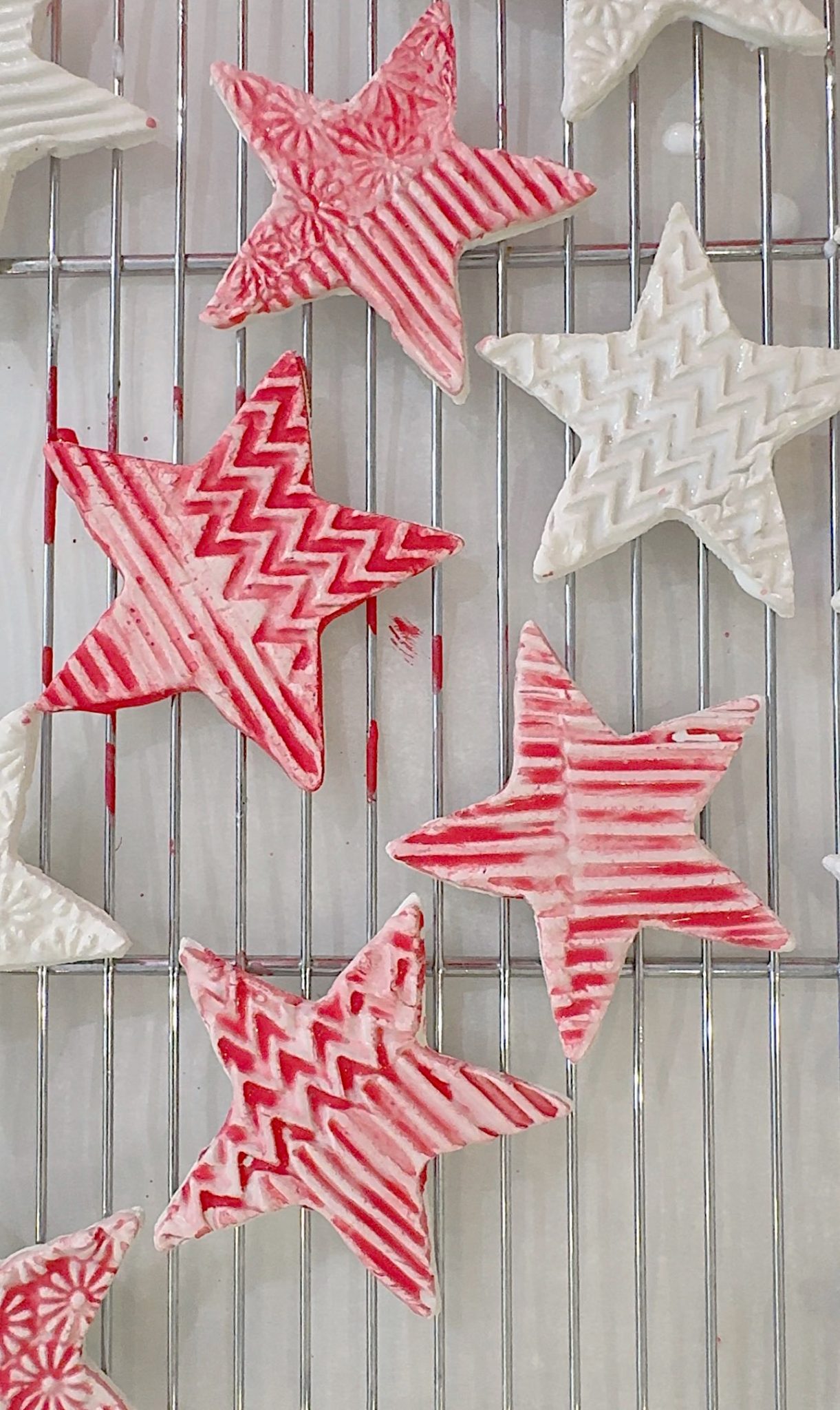 Red and white star-shaped cookies with textured patterns rest on a metal cooling rack.