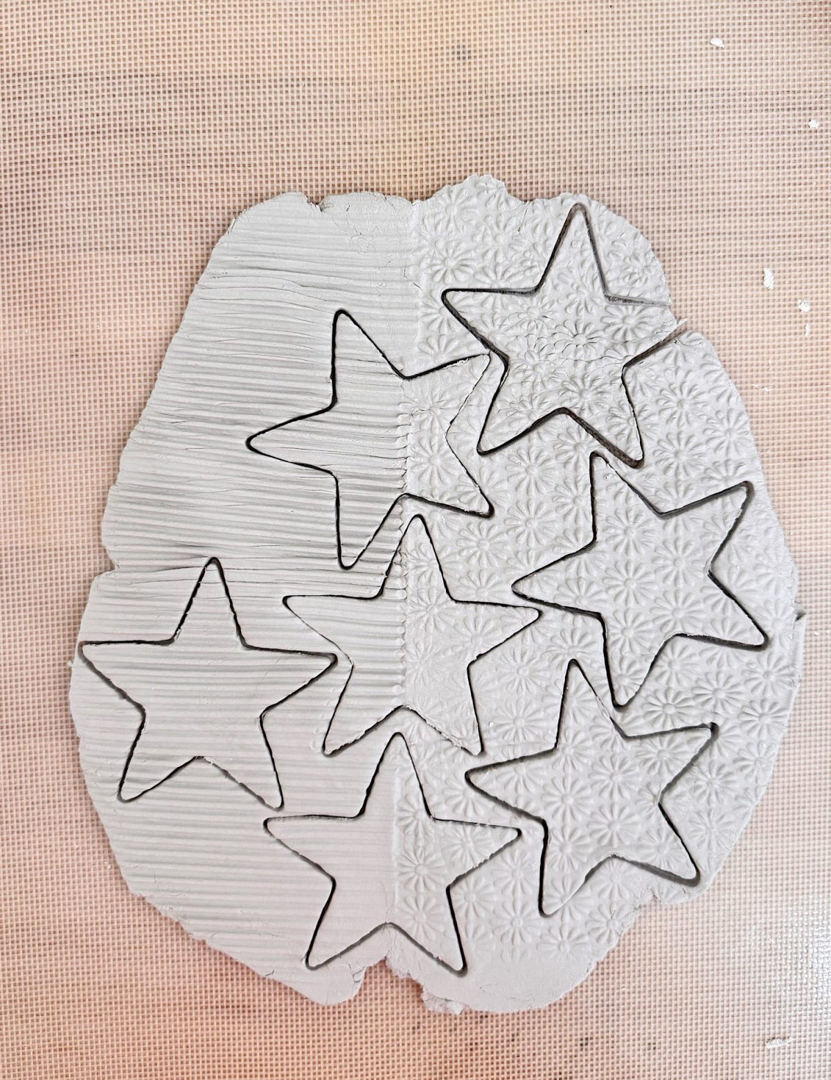 Slab of clay with eight star shapes cut out, showing various textured patterns on the surface.