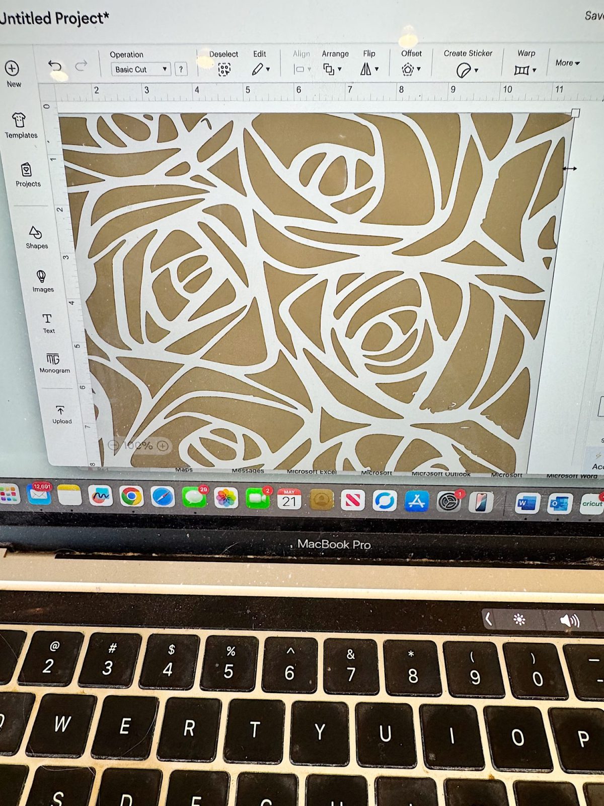 A laptop screen displays a floral cutout design in a graphic design program, with a MacBook Pro keyboard visible below.