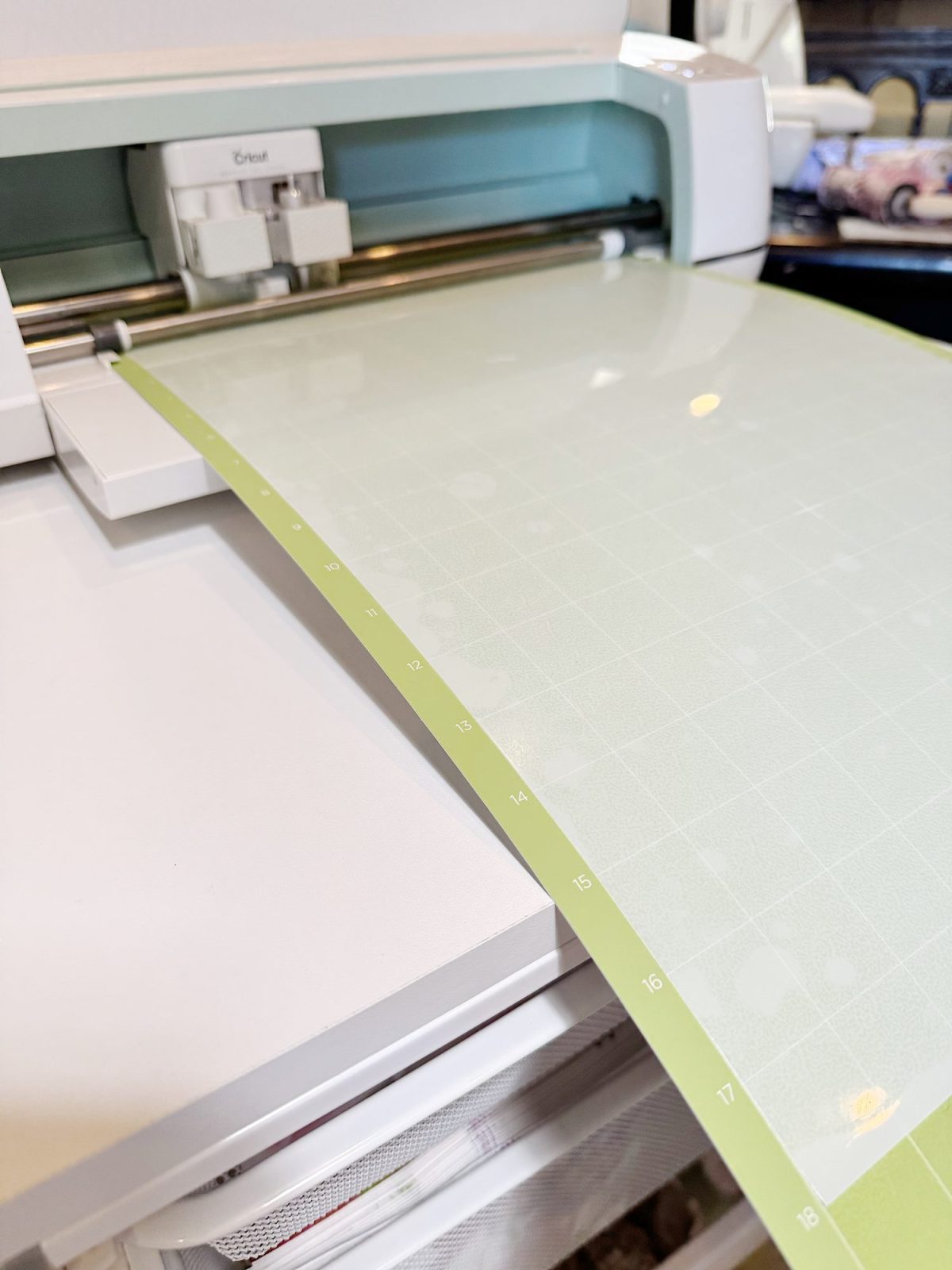 A Cricut cutting machine with a green cutting mat loaded, ready for use.