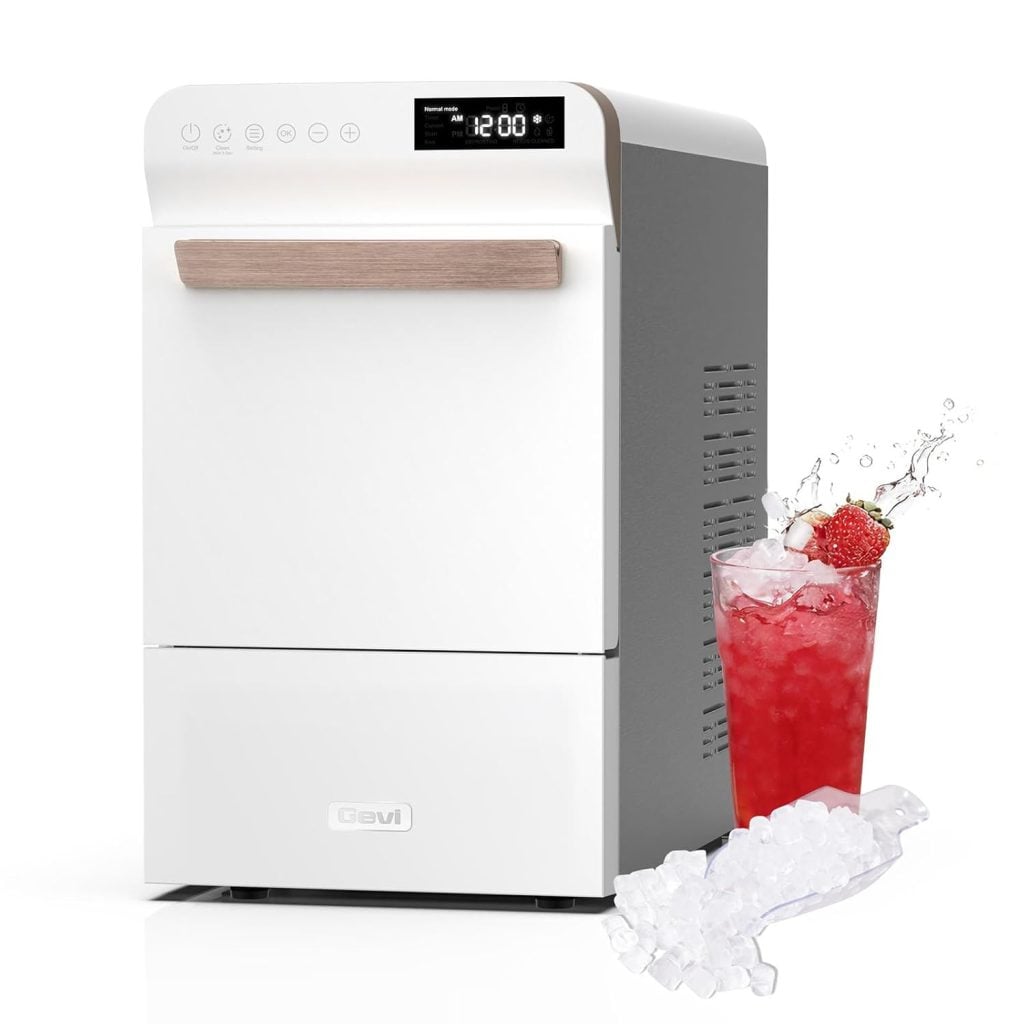 A compact white countertop ice maker with a digital display sits beside a glass of red iced drink, complete with ice cubes and a splash effect—perfect for cooling off on Amazon Prime Day.
