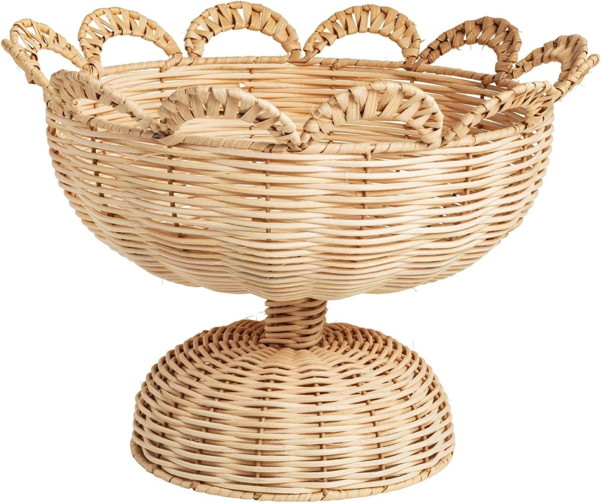 A woven wicker pedestal bowl with a scalloped edge detail, featuring a raised base and natural light brown color—perfect for displaying fresh fruit or as charming lemon decor.