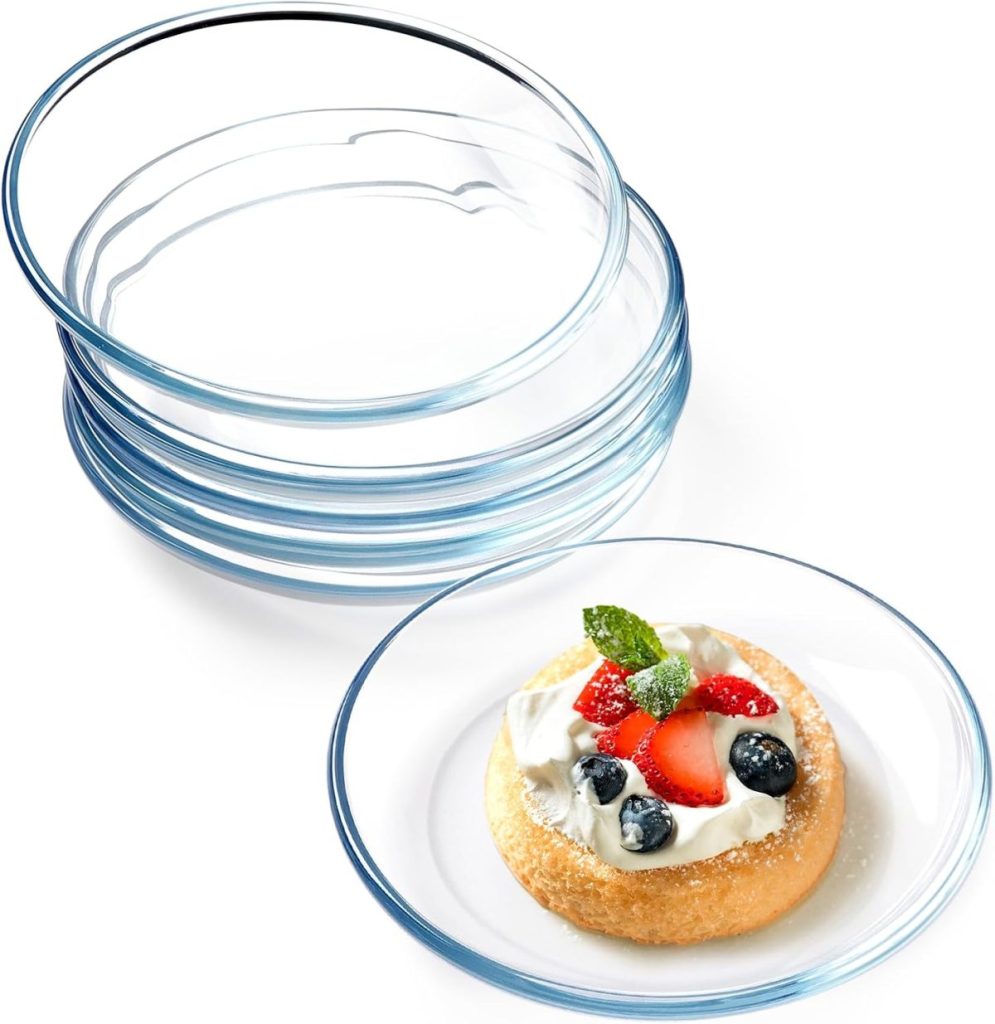 A stack of clear glass plates with one plate in front holding a dessert topped with cream, strawberries, blueberries, and a mint leaf—a delightful display perfect for showcasing your Creative Crafts at any gathering.