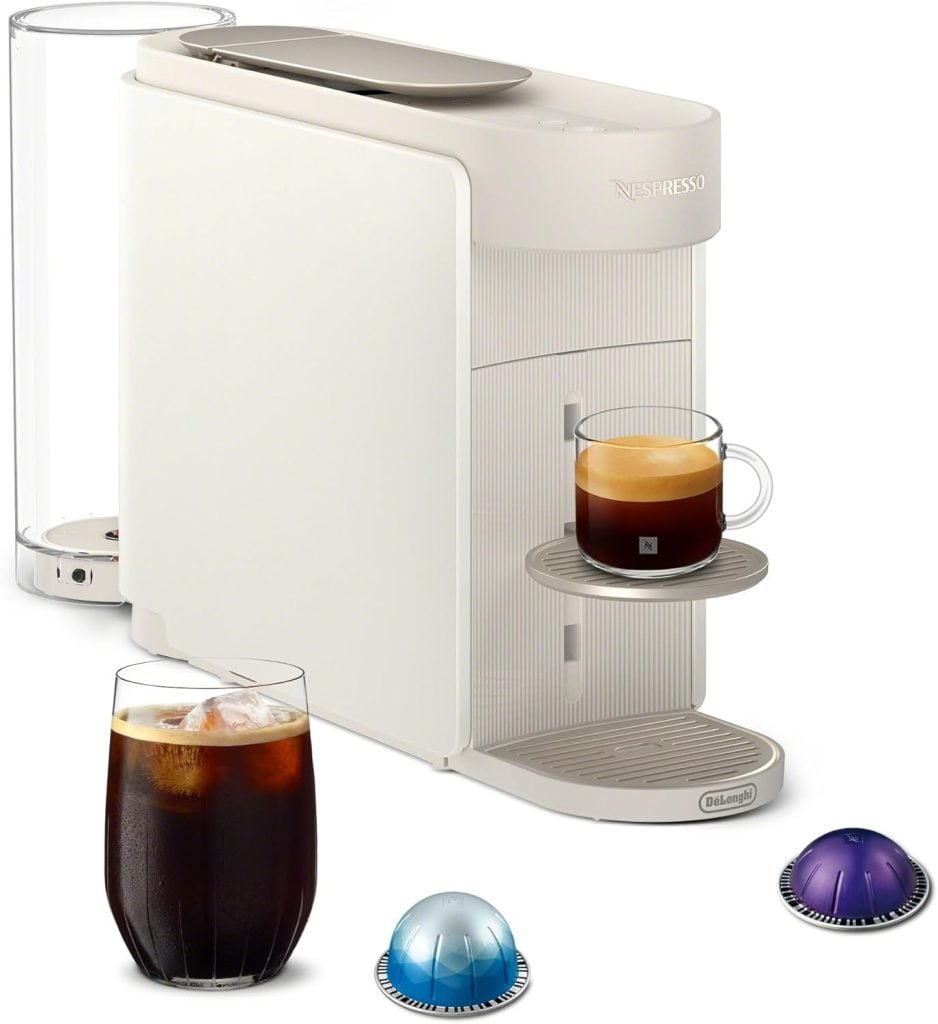 A white Nespresso machine with a clear water tank, a glass of iced coffee, a cup of espresso, and three colorful coffee capsules—perfect for Amazon Prime Day deals.