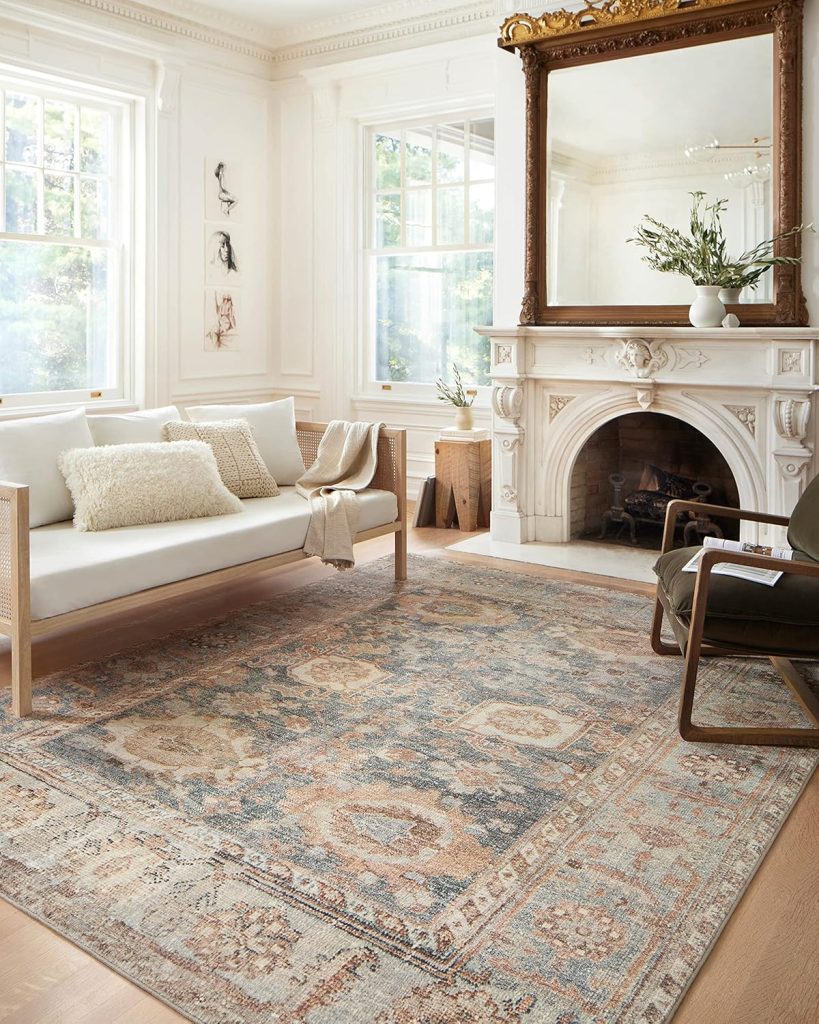 A sunlit living room with a white sofa, patterned area rug, ornate fireplace, and large mirror offers cozy elegance—perfect for finding decor inspiration ahead of Amazon Prime Day deals.