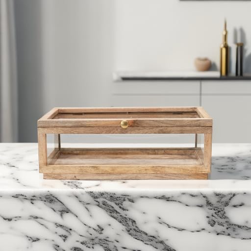 A rectangular wooden and glass display box with a brass knob sits on a white marble countertop in a modern kitchen.