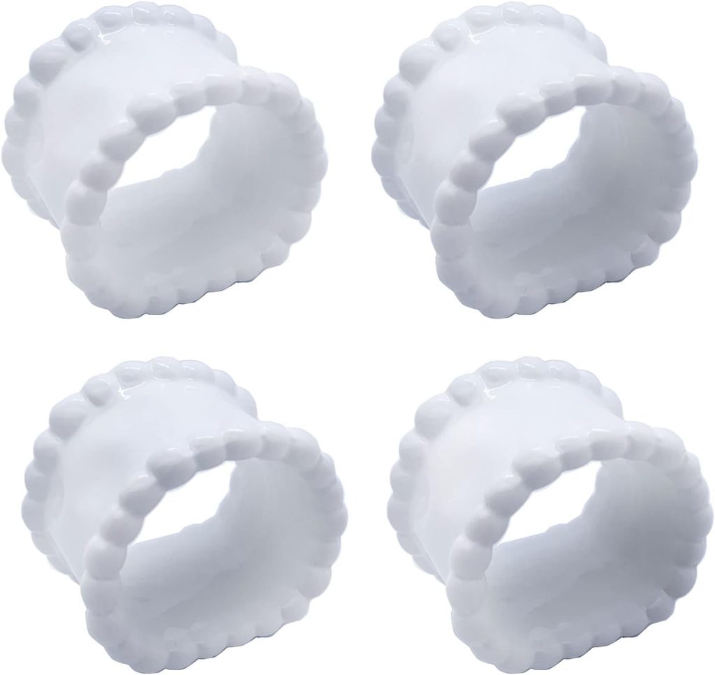 Four handmade clay napkin rings in white ceramic, featuring a beaded edge design, arranged in a two-by-two grid on a white background.