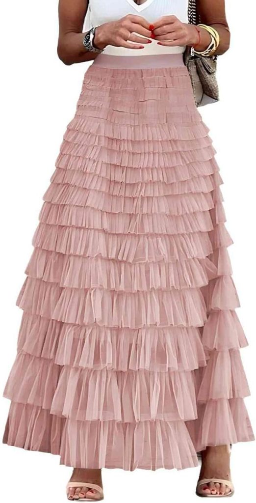 Woman wearing a sleeveless white top and a long, tiered pink ruffle skirt with sandals—an effortlessly chic look as fall is here, perfect for transitional style from summer to autumn.