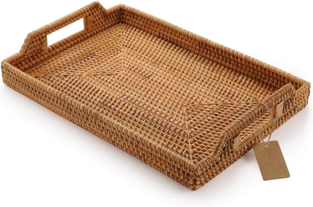 Rectangular woven rattan serving tray with raised sides, cut-out handles on each short end, and a small brown tag attached to one corner.