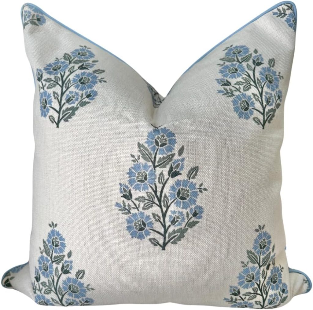 Square cushion with a white background featuring a repeating pattern of blue and green floral designs.