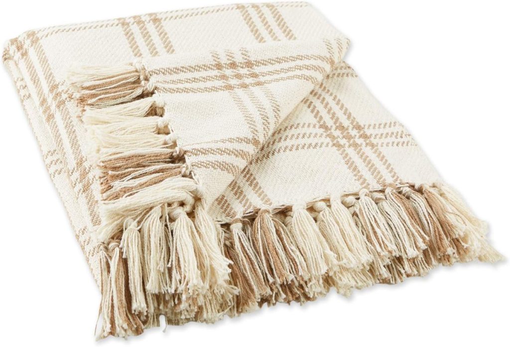 Folded beige and cream plaid throw blanket with fringed edges, displayed on a white background.