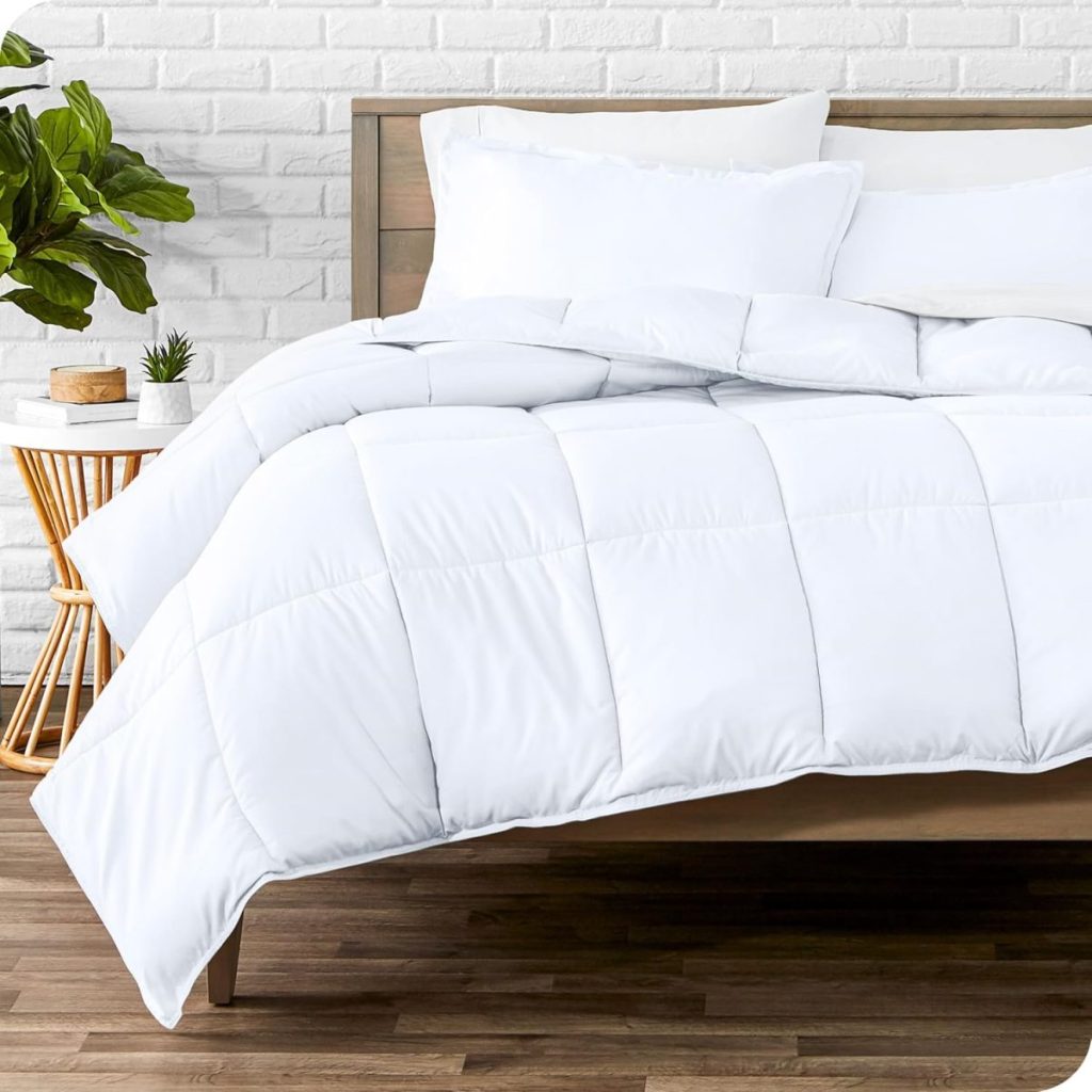 A neatly made bed with a white comforter and pillows, a wooden headboard, a side table with plants, and a white brick wall background.