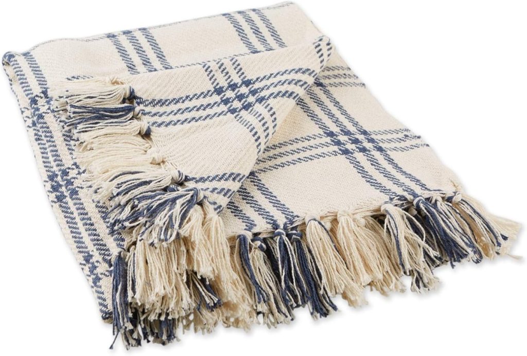 A folded beige and blue plaid throw blanket with fringed edges.