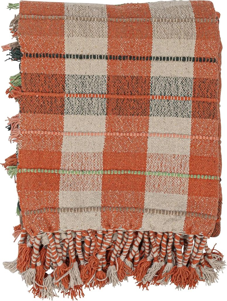 A folded woven blanket with an orange, beige, and brown plaid pattern and fringed edges.