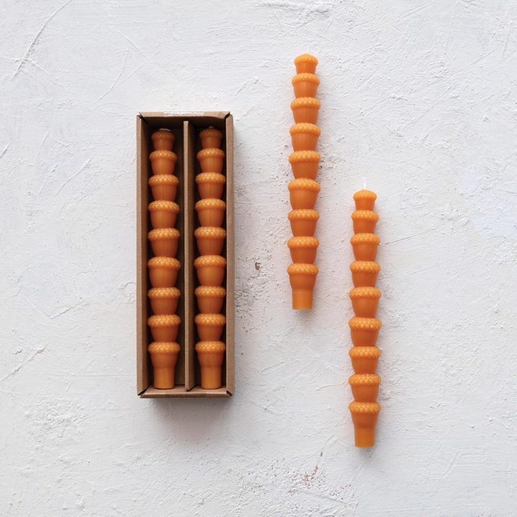 Two rows of stacked orange objects in a box are placed on a white textured surface, with two identical objects lying next to the box.