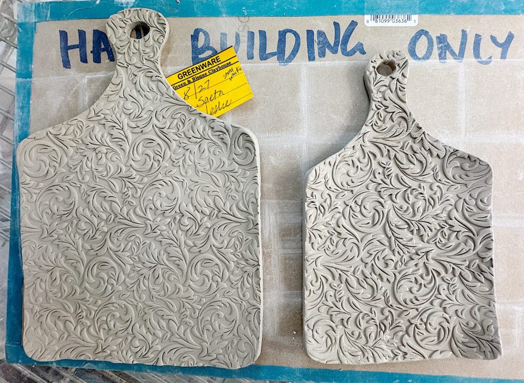 Two rectangular clay boards with handles, decorated with a raised swirling pattern, placed on a tray labeled "HAND BUILDING ONLY.
