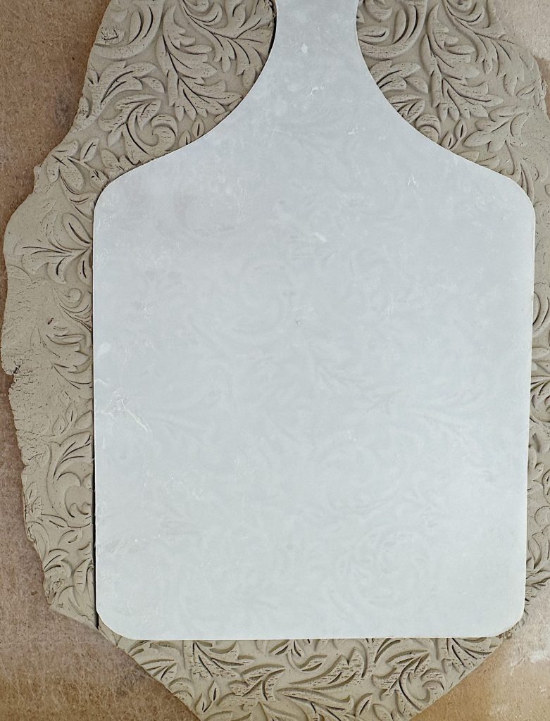 A slab of patterned clay with a rectangular section cut out, placed on a flat surface.